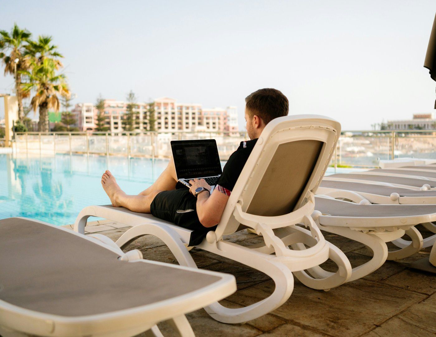 man at the pool working on his computer